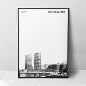 Puede incluir: Fotografía en blanco y negro del horizonte de Grand Rapids, con un puente y varios edificios. El texto "GRAND RAPIDS" está impreso en blanco en la parte superior de la imagen.