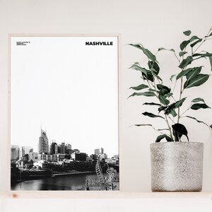 May include: A black and white photograph of the Nashville skyline, including the iconic AT&T building, in a wooden frame on a shelf with a potted plant.