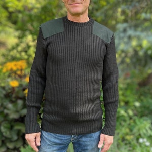May include: A black ribbed jumper with green suede shoulder patches. The jumper has a crew neck and long sleeves.