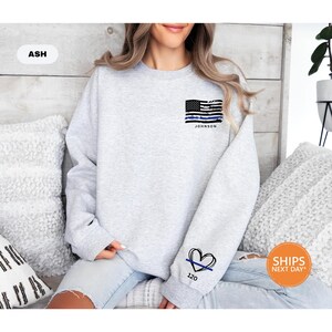 a woman sitting on a bed wearing a grey sweatshirt