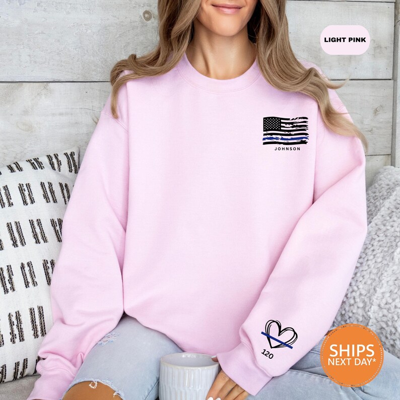 a woman sitting on a couch wearing a pink sweatshirt