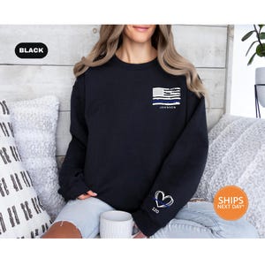 a woman sitting on a couch wearing a black sweatshirt