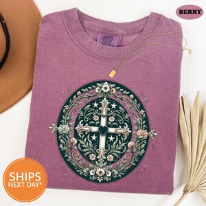 a purple t - shirt with a cross on it