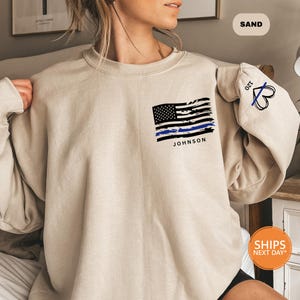 a woman sitting on a bed wearing a sweatshirt with an american flag on it