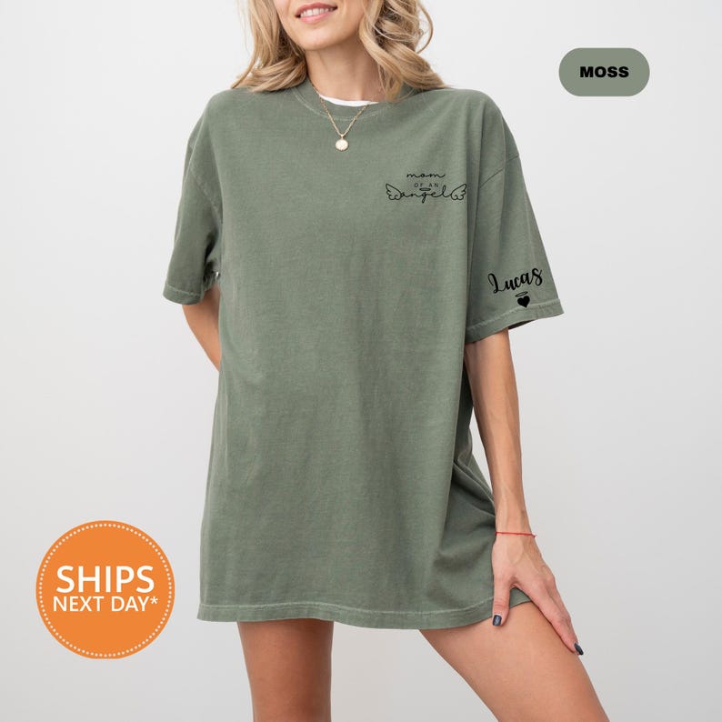 A woman wearing a green t-shirt with a graphic design on the front, posing against a white background.