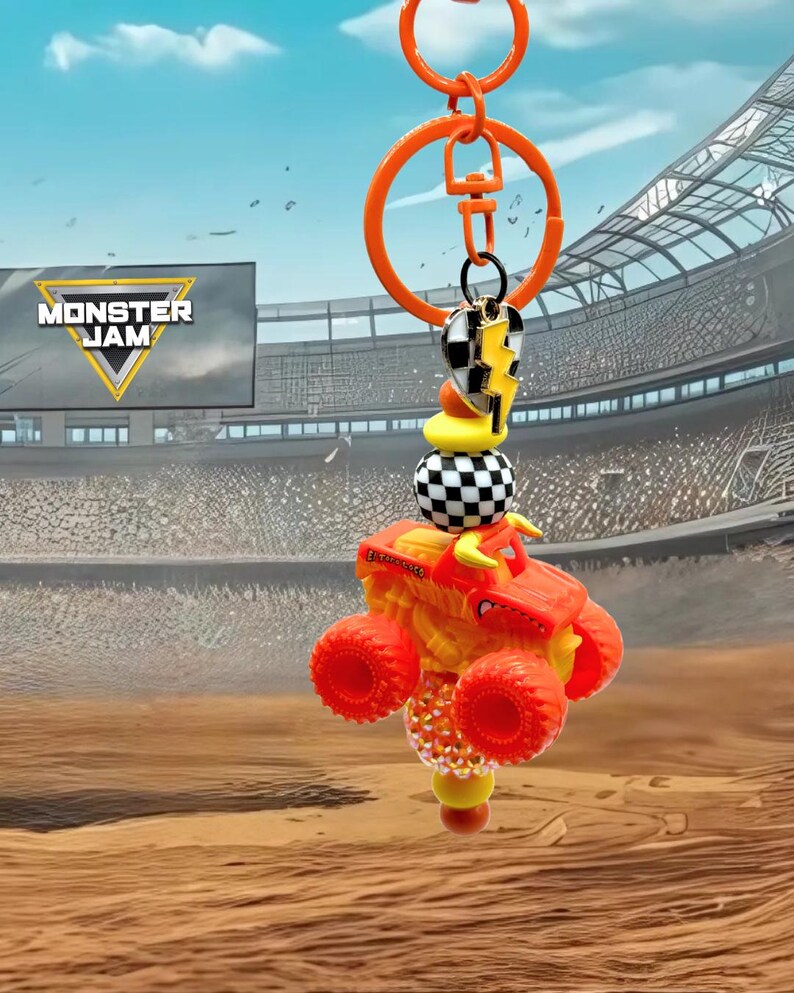 Pu&ograve; includere: Portachiavi arancione con un camion mostro in miniatura con ruote rosse e carrozzeria gialla e arancione. Il portachiavi include un ciondolo con un motivo a scacchi e la scritta "Monster Jam".