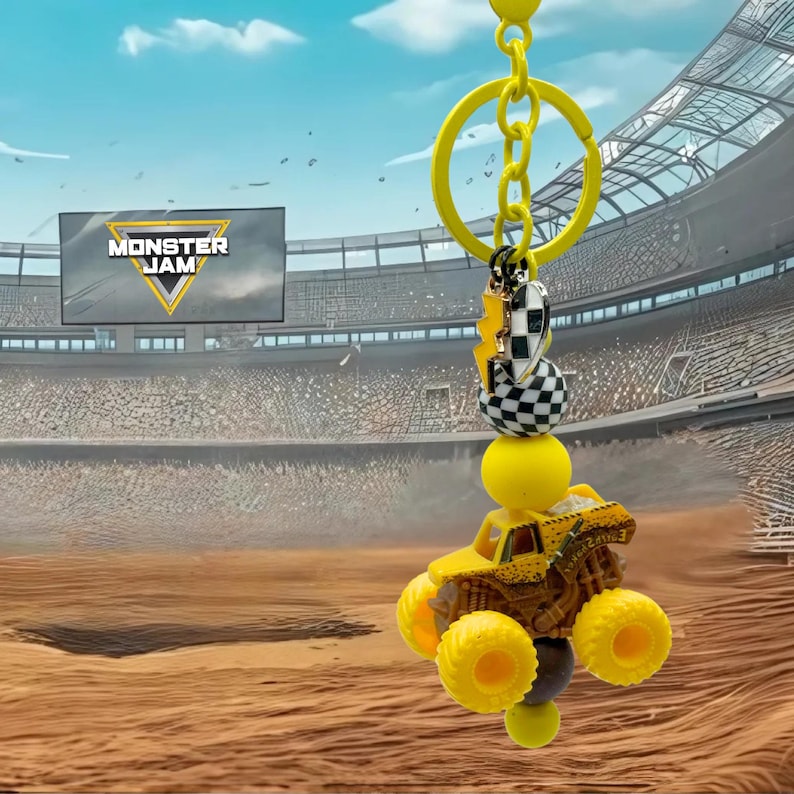 Pu&ograve; includere: Portachiavi giallo Monster Jam con un camion mostro in miniatura con ruote oversize. Il portachiavi include una catena gialla, una perlina a scacchi e un ciondolo a forma di fulmine. Lo sfondo mostra uno stadio con il logo Monster Jam.