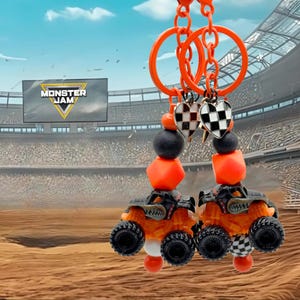 Pu&ograve; includere: Due portachiavi arancioni con ciondoli a forma di camion Monster Jam. Ogni portachiavi presenta un monster truck nero e arancione, perline arancioni, perline nere e un ciondolo a forma di cuore con un motivo a scacchi. I portachiavi sono sospesi ad anelli arancioni.