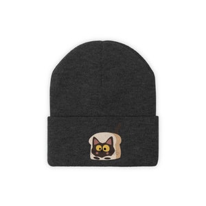 May include: A dark gray beanie featuring an embroidered design of a black cat inside a slice of toast. The cat has yellow eyes and a brown outline. The beanie is a winter accessory.