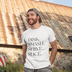 May include: A white t-shirt with the text "DINK. SMASH. SERVE. SLICE." printed in black.