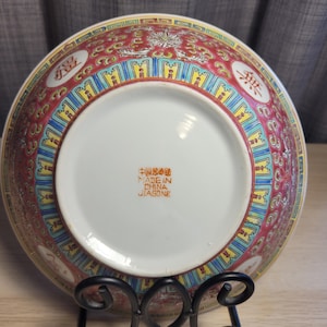 May include: A red and white porcelain bowl with a floral design and Chinese characters. The bowl has a blue and yellow border and the words "Made in China Jiagong" are printed on the bottom.