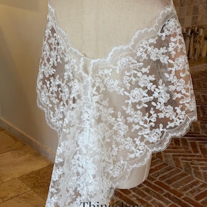 May include: A white lace bridal veil draped over a mannequin. The veil features a floral pattern and scalloped edges. The text "Thingsbox Handmade Bridal Veils" is visible at the bottom.