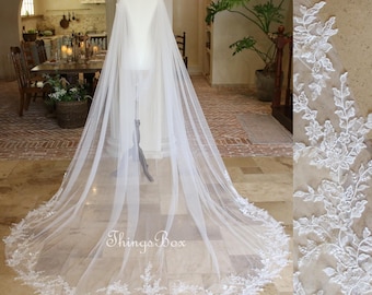 May include: A white tulle wedding veil with a delicate floral lace trim. The veil is long and flowing, and the lace trim is intricate and beautiful.