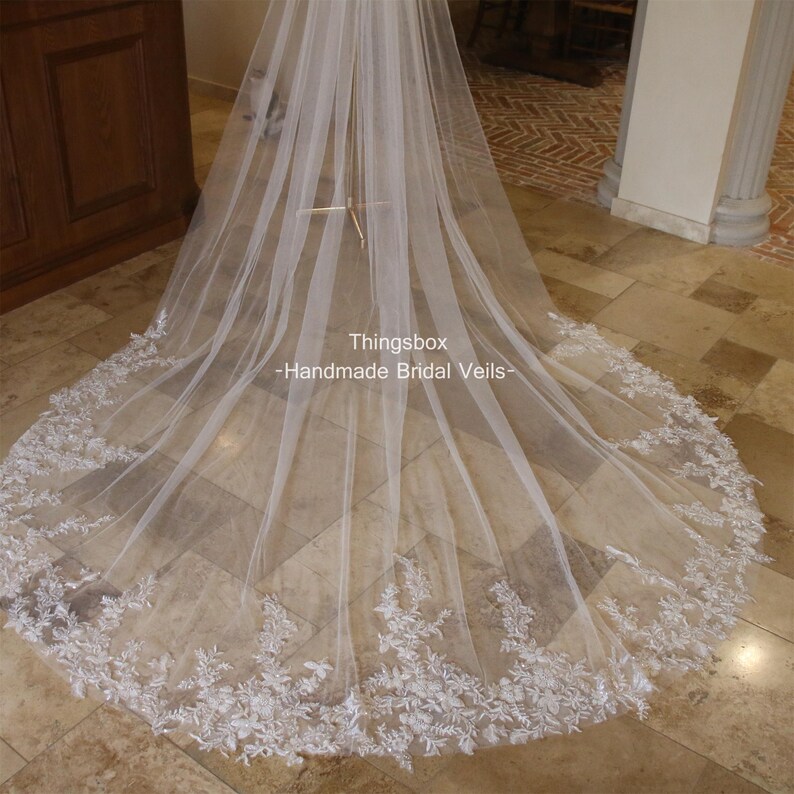 May include: A white bridal veil with a delicate lace trim. The veil is long and flowing, and the lace trim is intricate and beautiful. The veil is made of soft tulle and is perfect for a wedding.