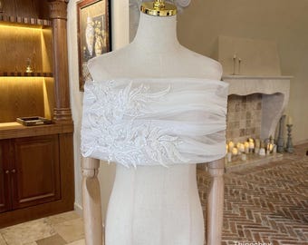 May include: A white bridal veil, draped over a mannequin, features intricate floral embroidery and beadwork. The veil is made of a sheer, flowing fabric. The text "Thingsbox Handmade Bridal Veils" is visible at the bottom.