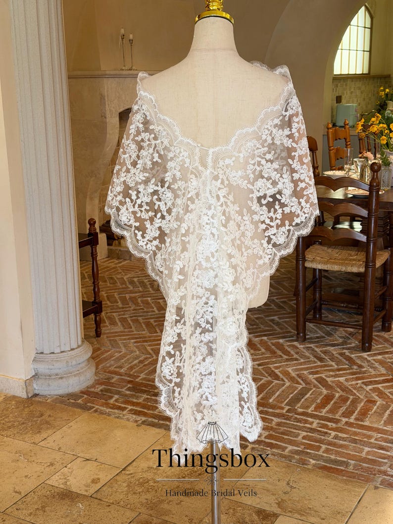 May include: A white, floral lace bridal veil displayed on a mannequin. The veil has a scalloped edge and a long, flowing design. The text "Thingsbox Handmade Bridal Veils" is visible at the bottom.