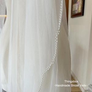 Könnte beinhalten: Ein weißer Braut Schleier mit einer Reihe von Perlen am Rand. Thingsbox - Handgefertigte Brautschleier.