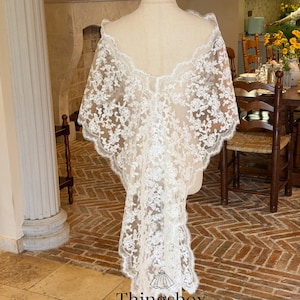 May include: A white lace bridal veil with floral patterns is draped over a mannequin. The veil has a scalloped edge and a flowing design. The text "Thingsbox" and "Handmade Bridal Veils" are visible at the bottom.