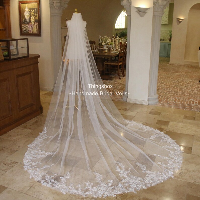 May include: A long, white bridal veil with a delicate lace trim. The veil is made of soft tulle and is perfect for a classic wedding look.