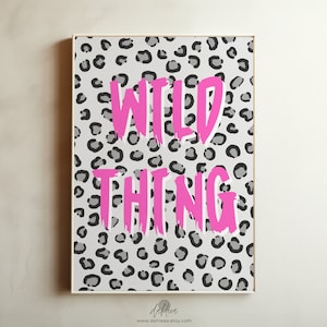 May include: A printable wall art design featuring a grey and white leopard print background with the text "WILD THING" in pink.
