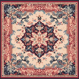 Puede incluir: Una alfombra cuadrada detallada con un intrincado patrón floral y geométrico. La alfombra presenta un medallón central en azul marino, crema y coral, rodeado de motivos florales y un borde en tonos rojos y azul marino. El diseño es simétrico.
