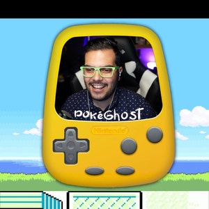 Könnte beinhalten: Ein gelbes Handheld-Spielgerät mit einer Person darin, die lächelt und eine grüne Brille trägt. Das Gerät hat ein Steuerkreuz, Knöpfe und den Text "pokeGhost" und "Nintendo". Der Hintergrund ist eine pixelige Landschaft.