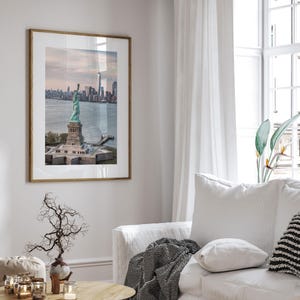 a framed photograph of the Statue of Liberty in New York City, with the city skyline visible in the background.