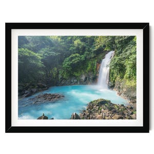 A serene waterfall cascades into a turquoise pool surrounded by lush, verdant foliage in a tranquil forest setting.