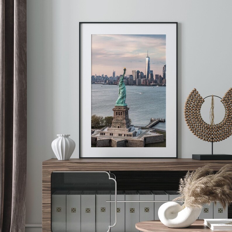 a framed photograph of the Statue of Liberty in New York City, with the city skyline in the background.