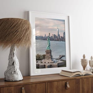 a framed photograph of the Statue of Liberty in New York City, with the city skyline in the background.