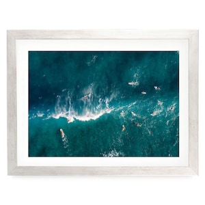 a group of people surfing on a large, turquoise ocean wave.