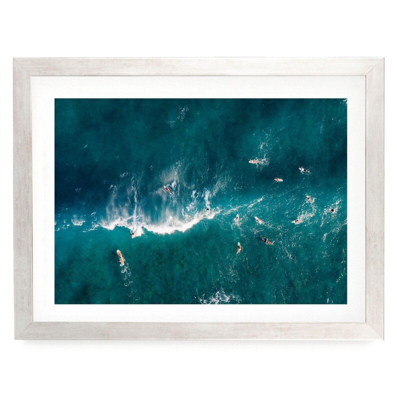 a group of people surfing on a large, turquoise ocean wave.