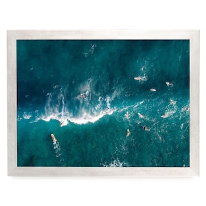 a group of people surfing in the ocean, with waves crashing around them.