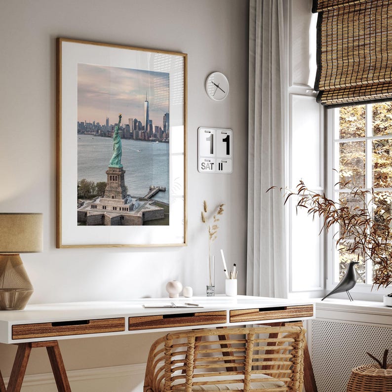 a modern and minimalist interior design with a large framed picture of the Statue of Liberty hanging on the wall above a white desk with a lamp and a bird figurine.