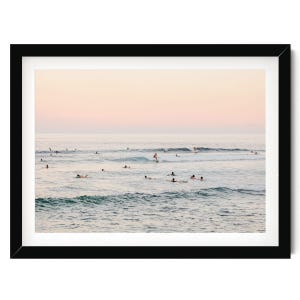 A group of people enjoying a day at the beach, with some of them surfing on the waves.