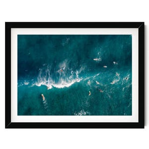 an aerial view of surfers riding a wave in the ocean