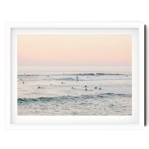 a group of people swimming and surfing in the ocean, with waves visible in the background.