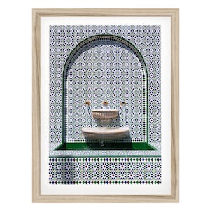 May include: A framed wall art print featuring a stone fountain set within an arched alcove. The fountain and surrounding wall are covered in intricate geometric tiles in shades of blue, green, and white. Three small spouts release water.