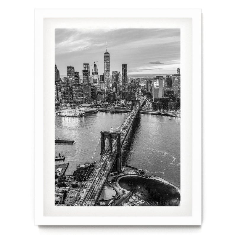 A black and white aerial view of the Brooklyn Bridge and the surrounding cityscape of New York City.