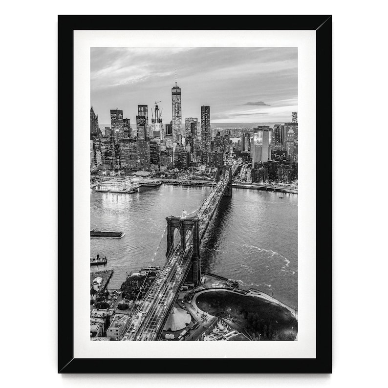 A black and white aerial view of the Brooklyn Bridge and the surrounding cityscape of New York City.