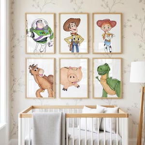 May include: Six framed watercolor prints featuring characters from the animated film Toy Story. The characters include Buzz Lightyear, Woody, Jessie, Bullseye, Hamm, and Rex. The prints are displayed above a white crib with a gray blanket.