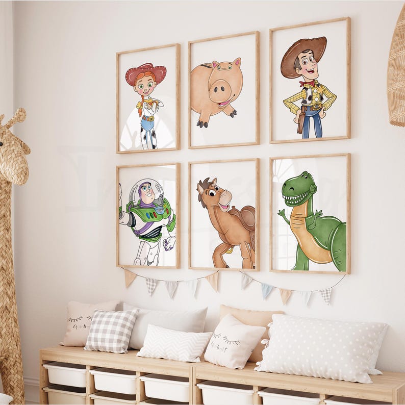 May include: Six framed art prints featuring characters from a popular animated movie. The prints are in wooden frames and are hung on a white wall. Below the prints are pillows and a wooden storage unit. The characters include a cowgirl, a pig, a cowboy, a space ranger, a horse, and a dinosaur.