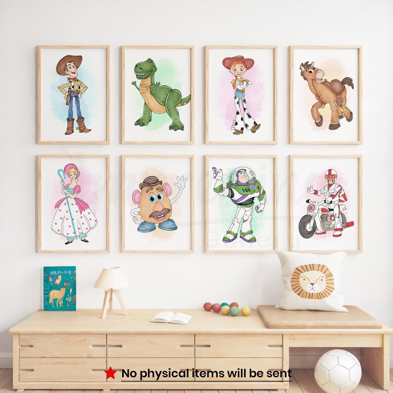 Peut inclure: Huit impressions d'art encadr&eacute;es repr&eacute;sentant des personnages de dessins anim&eacute;s, dont un cow-boy, un dinosaure, une cow-girl, un cheval, une poup&eacute;e, M. Patate, un astronaute et un motard. Les impressions sont expos&eacute;es sur un mur blanc au-dessus d'un meuble en bois.