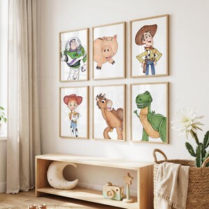 May include: Six framed watercolor prints featuring characters from the animated film Toy Story. The prints include Buzz Lightyear, Hamm the pig, Woody, Jessie, Bullseye, and Rex the dinosaur. The frames are a light brown color and are mounted on a white wall.