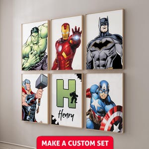 May include: Six framed superhero art prints featuring Hulk, Iron Man, Batman, Thor, Captain America, and a personalized print with the name "Henry". The prints have a white background and are in gold frames. The bottom of the image has the text "MAKE A CUSTOM SET".