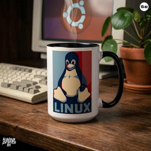 Puede incluir: Una taza de café blanca de 444 ml con asa e interior negros. La taza presenta un gráfico de pingüino con la palabra "LINUX" en un diseño azul, rojo y blanco. Sale vapor de la taza, lo que sugiere una bebida caliente.