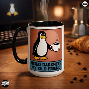 Puede incluir: Una taza de café blanca de 444 ml con asa y borde negros. La taza presenta un pingüino de dibujos animados sosteniendo una taza de café, con el texto "HELLO DARKNESS MY OLD FRIEND". Sale vapor de la taza.