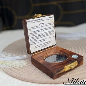 May include: A wooden box with a brass latch, containing a spherical densiometer. The box has instructions for using the densiometer, which is an instrument for measuring forest canopy density. Model-A.