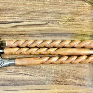 May include: Three wooden walking sticks with a twisted design. The top stick has a decorative metal bird head handle.