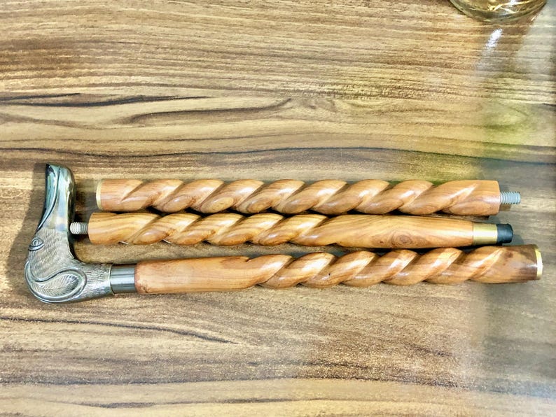 May include: Three wooden walking sticks with a twisted design. The top stick has a decorative metal bird head handle.